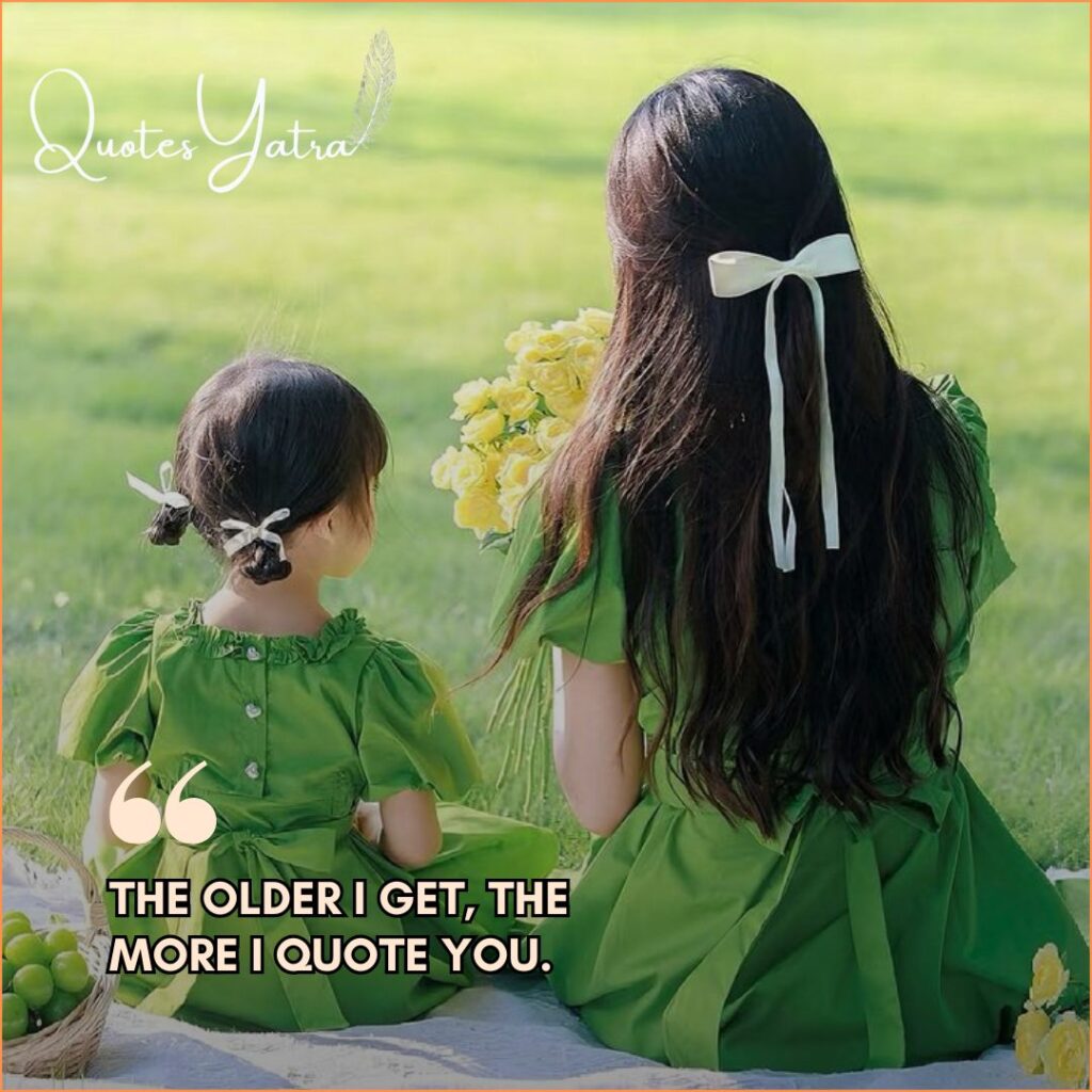 mother and daughter in green dresses sitting together on a picnic blanket in a sunny field.