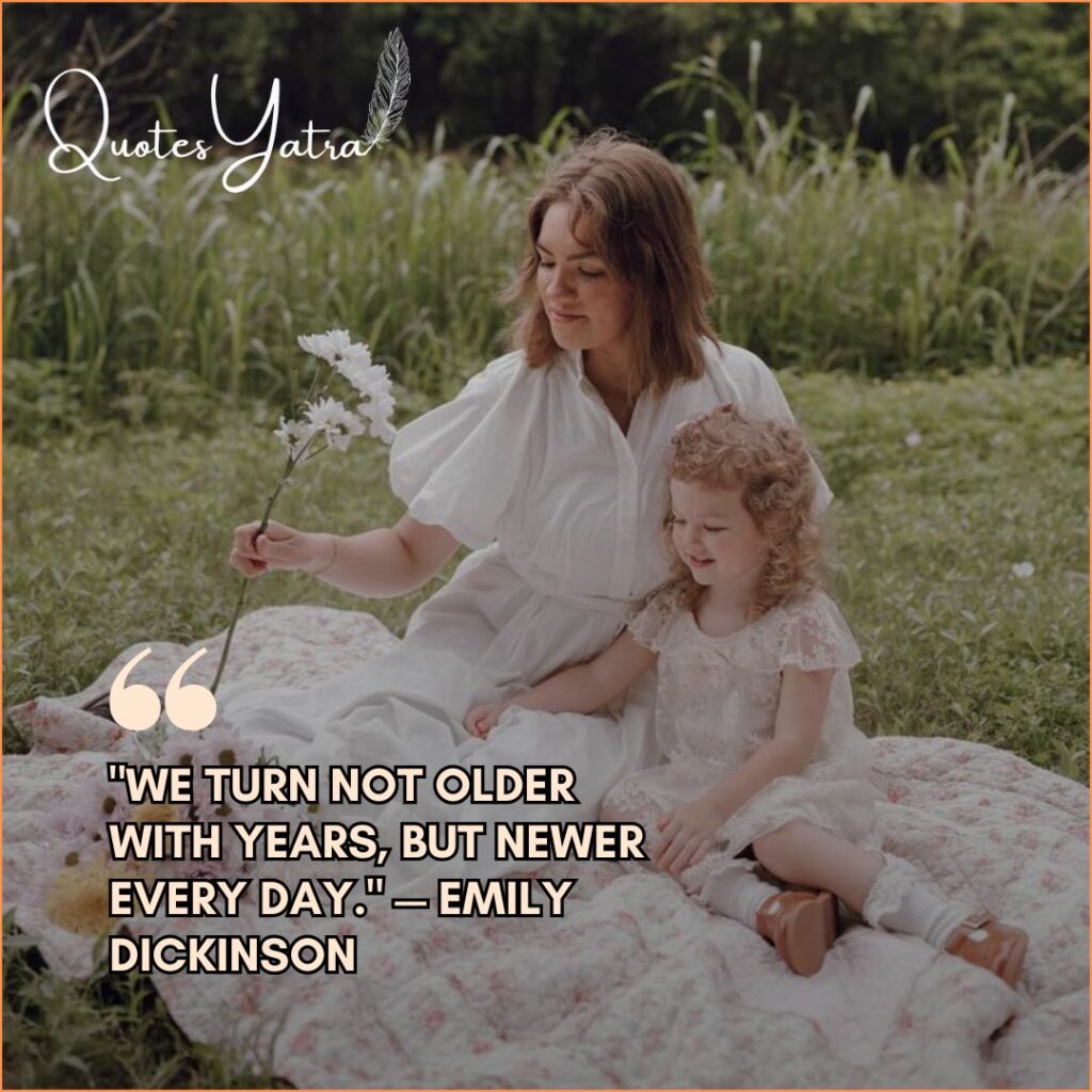 A mother and daughter sitting together on a blanket outdoors, holding flowers.